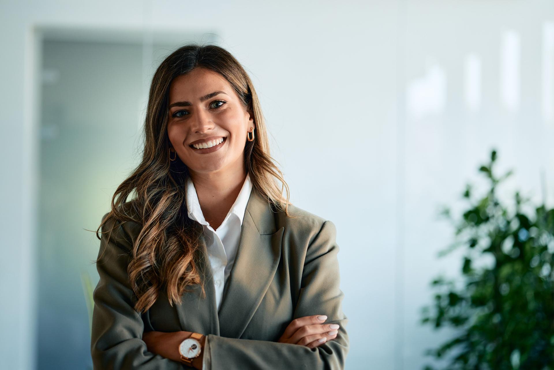 Portrait of a smiling businesswoman standing with arms crossed in a modern office