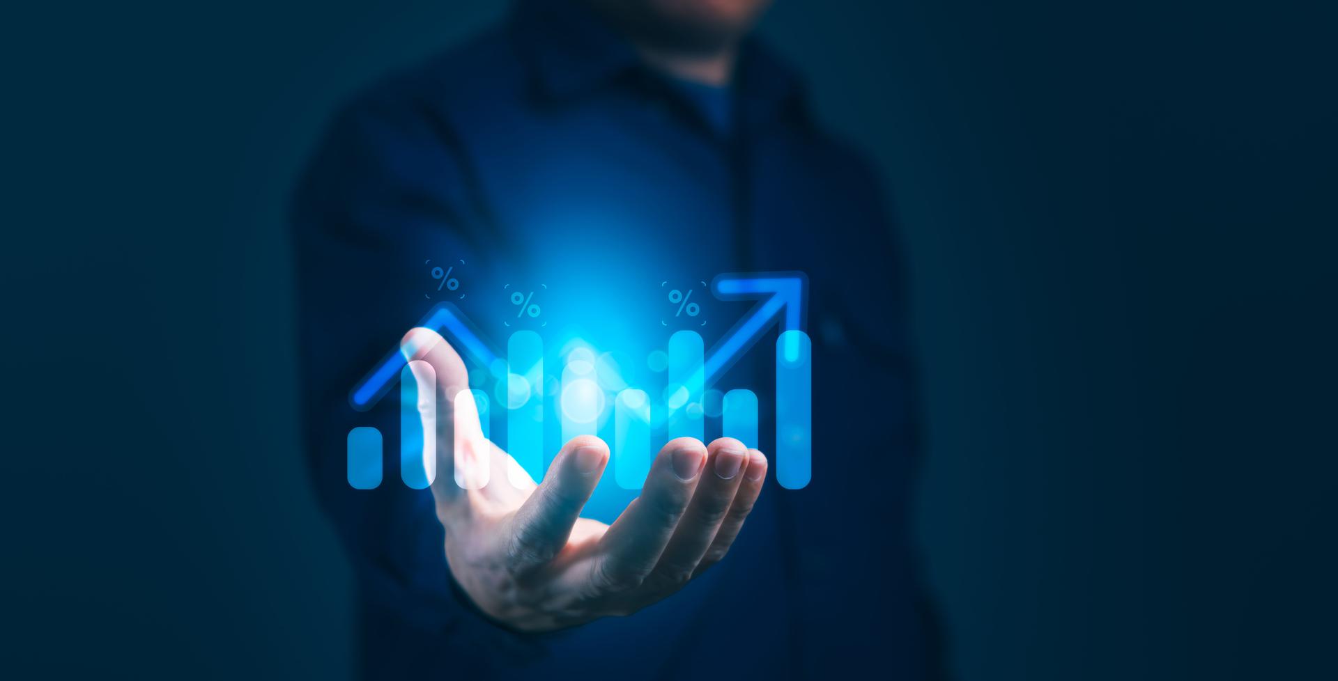 A businessman is holding a hand up to a blue screen with a graph of a rising line